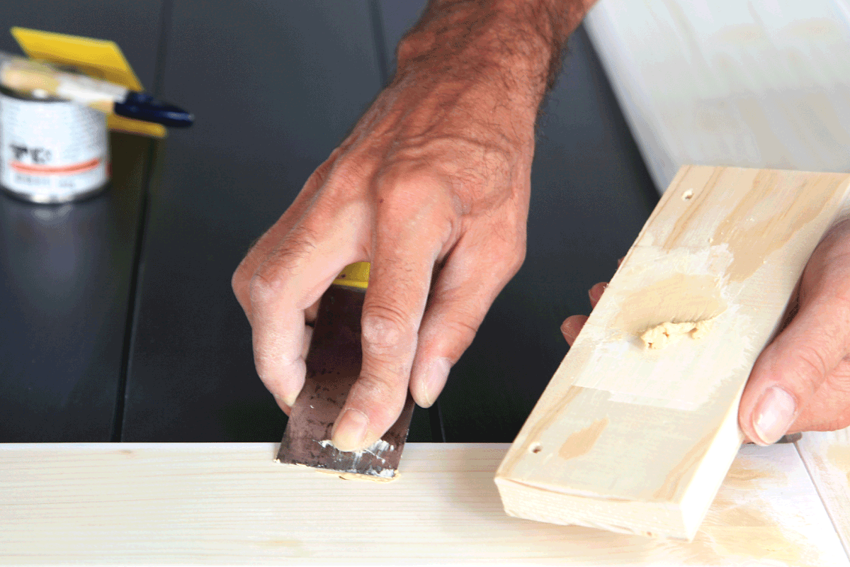 Putty knife in man's hand. DIY worker applying filler to the wood. Removing holes from a wood surface. How Long Does It Take For Wood Filler To Dry