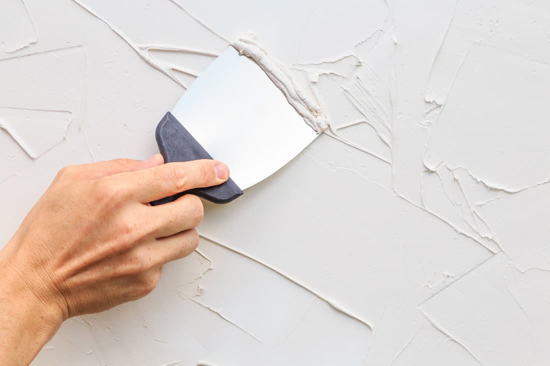 Removing putty on the wall using a putty knife