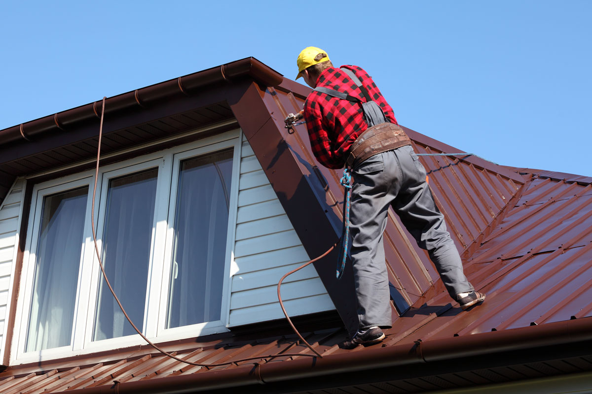 Roof installer riviting the metal roofing