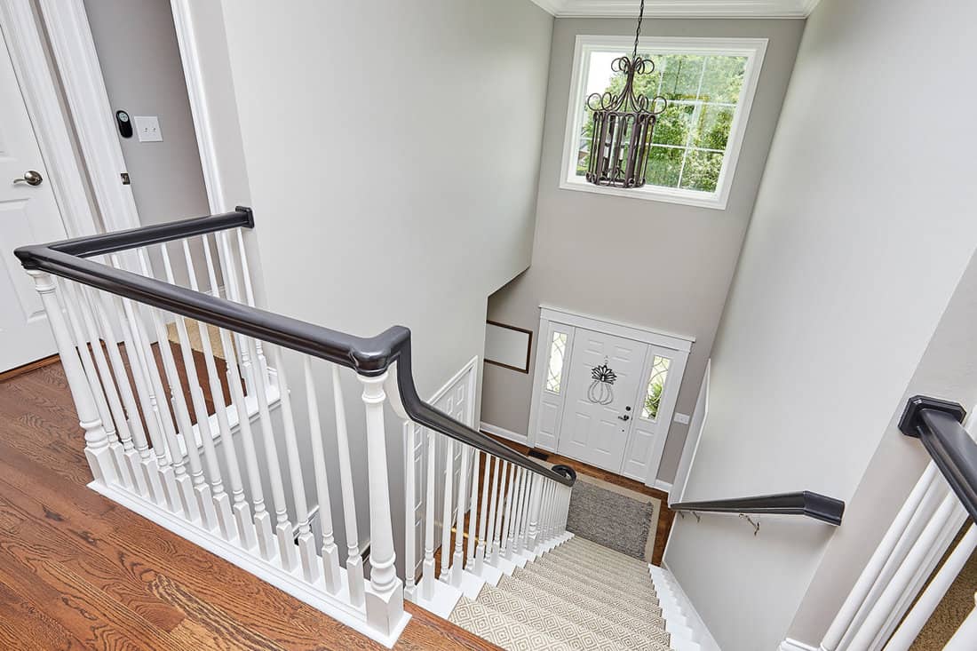 Second story of a house with wooden flooring, white painted stair banisters and dark handrails