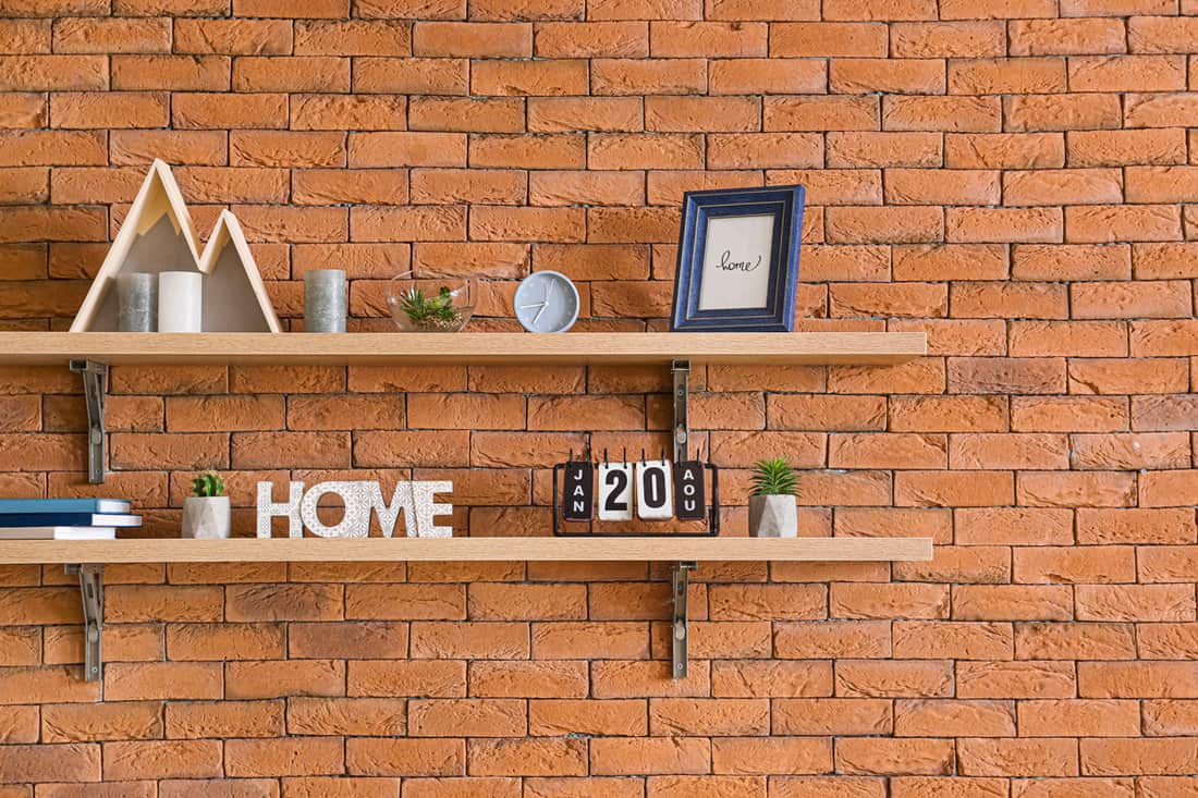 Shelves with decor hanging on brick wall