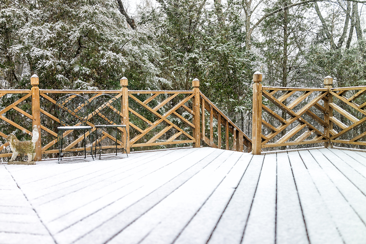 Snow covered wooden deck of house with statue decorations