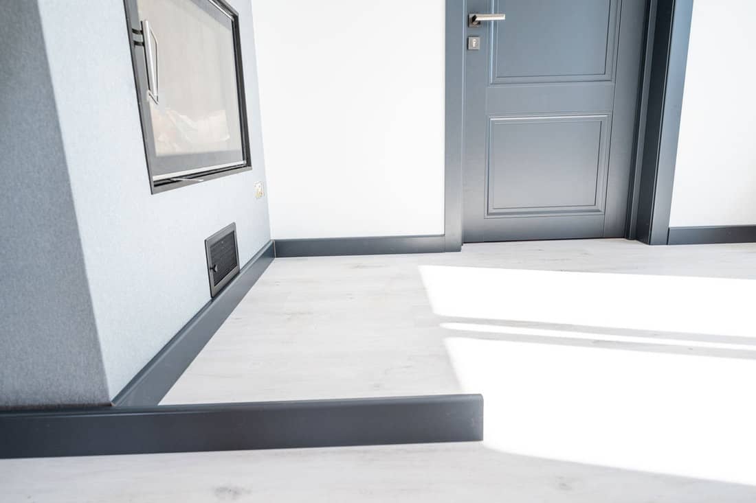The plinth is dark gray to match the color of the door, mounting the plinth in the room, light gray floor and dark plinth. 