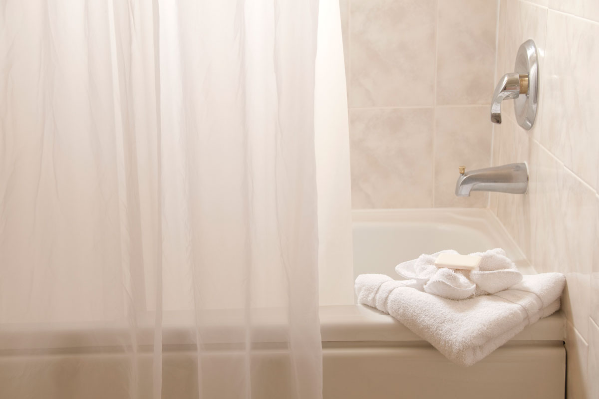 White bathroom with bathtub, towels and a shower curtain