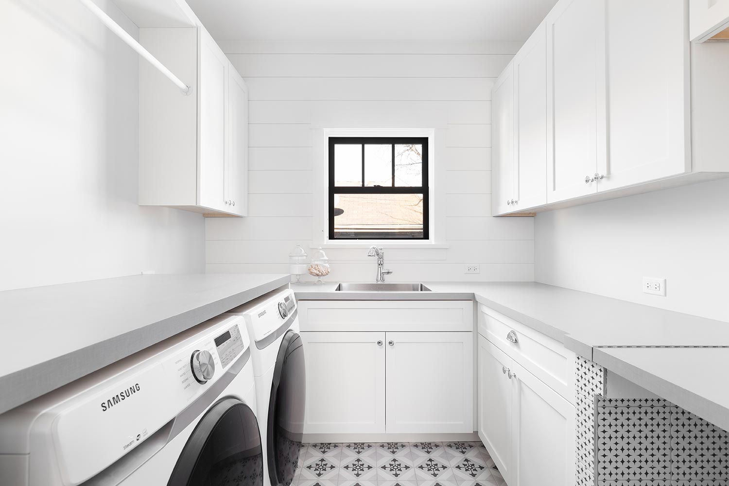White laundry room with a mosaic tile floor and shiplap wall