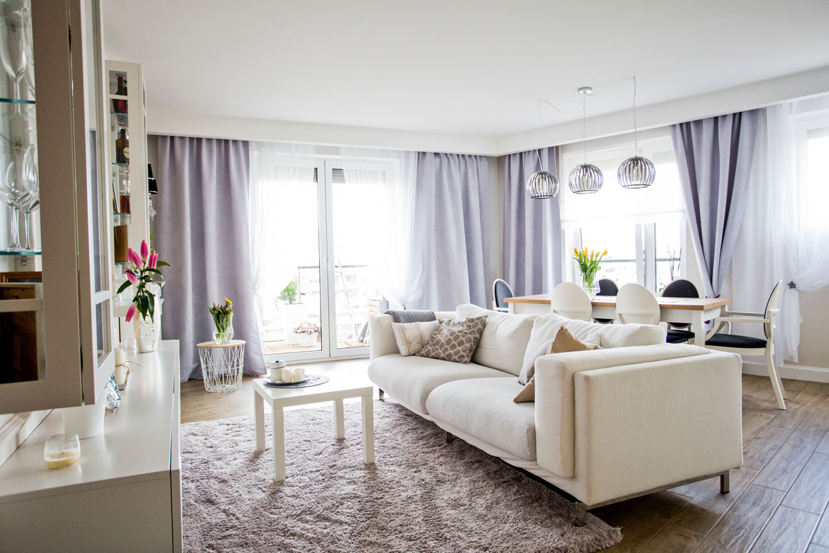 White room with sofa with a light violet curtains and low ceiling