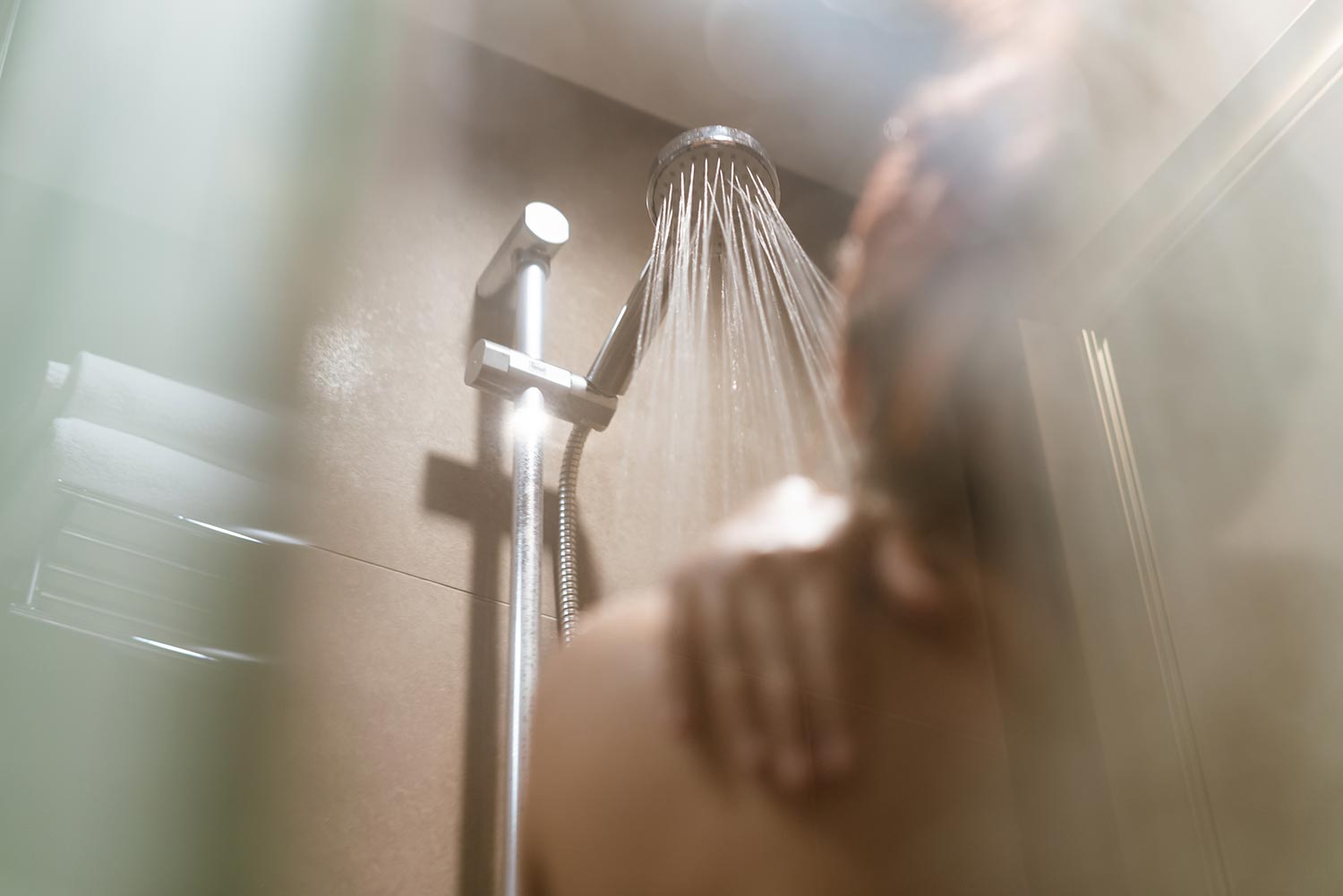 Woman taking a shower in the bathroom with hot steam filling the room