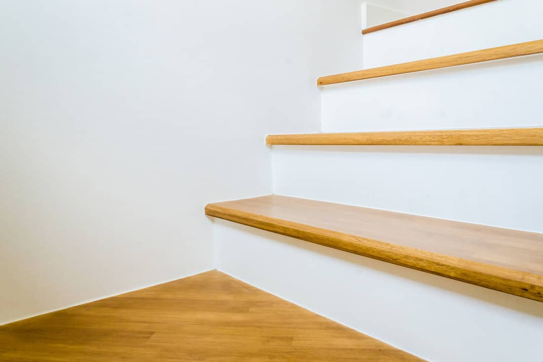 Wooden steps on the staircase and white painted walls