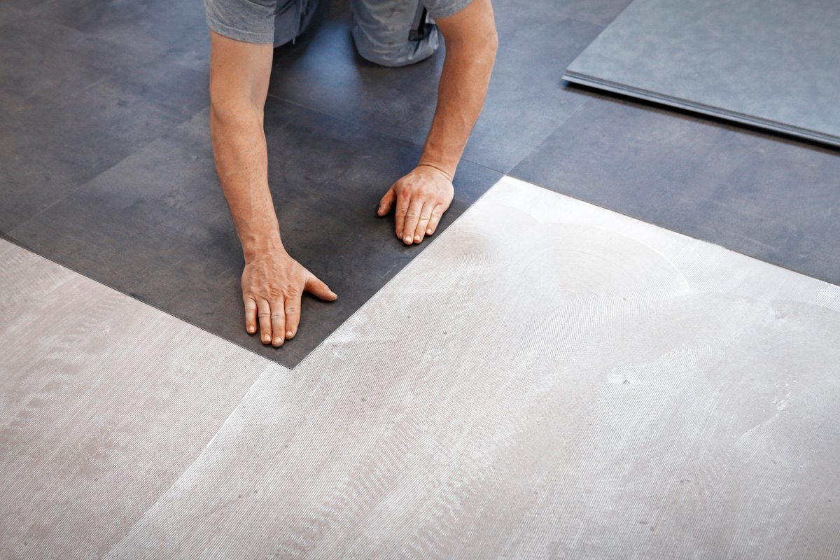 Worker making flooring with vinyl tiles