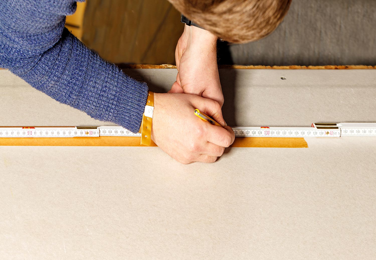 Worker mark out a sheet of drywall with a pencil