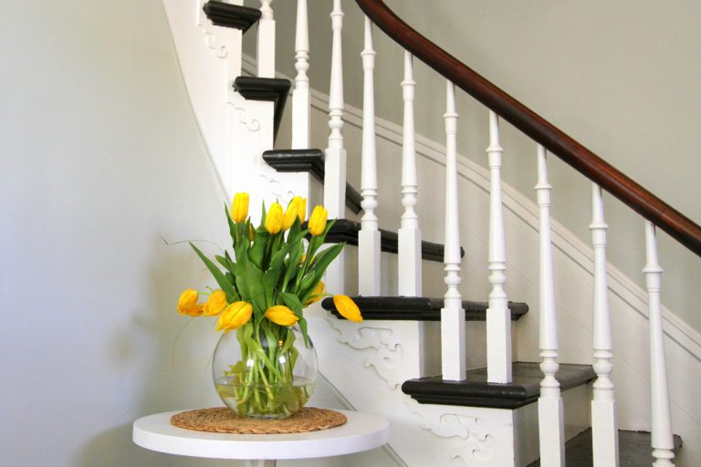 Yellow tulips on a round table beside heritage staircase, How Much Space Between Stair Spindles?