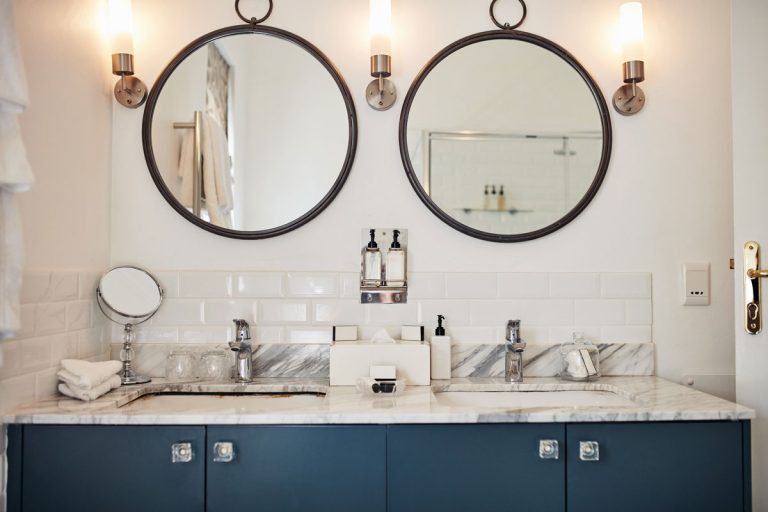 A bathroom at a modern hotel with two mirrors in a wall, What Color Mirror With Brushed Nickel Faucets?