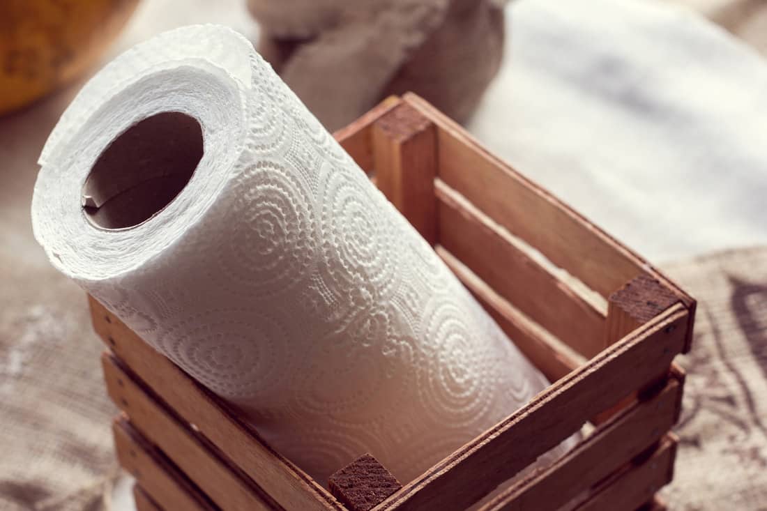 A white roll of paper towels in a wooden box