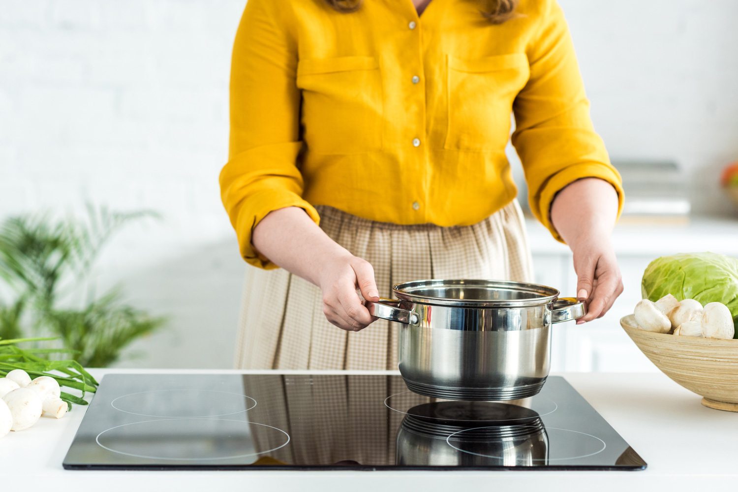 cropped image of woman putting pan on electric stove in kitchen