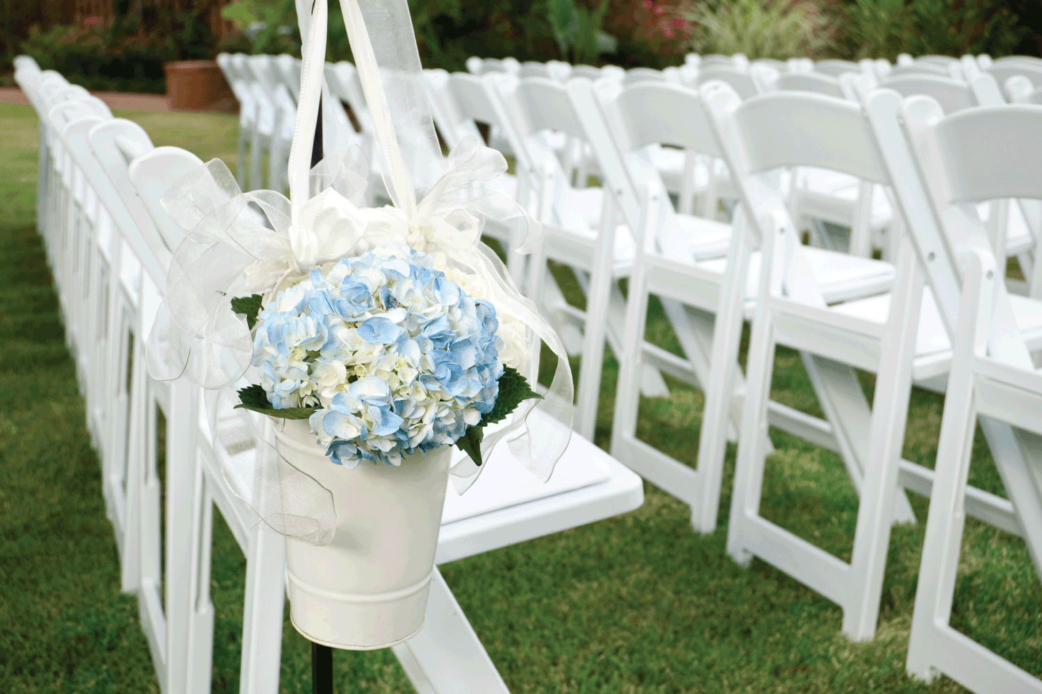 rows of white folding chairs and flower hung on the wedding aisle