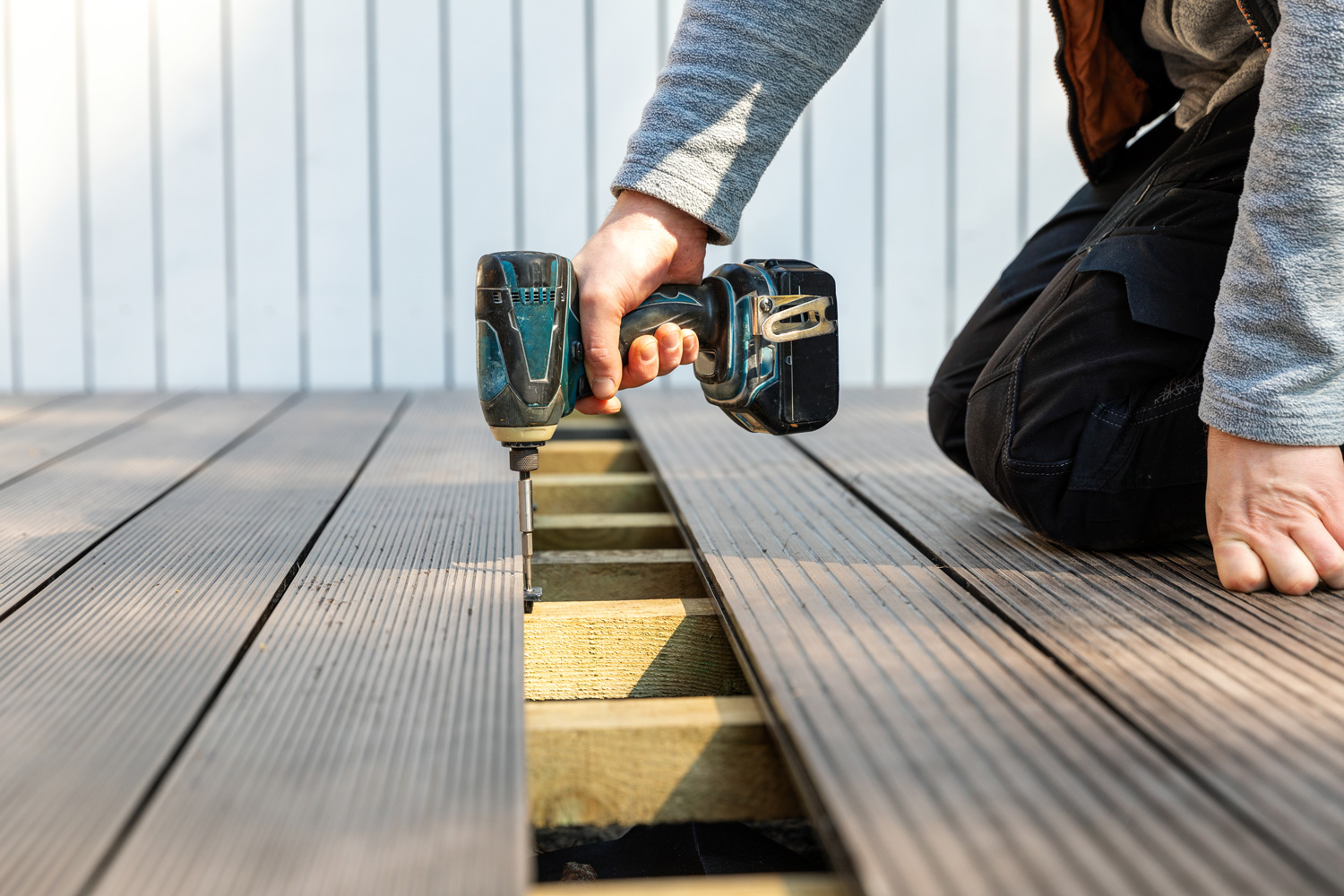 terrace deck construction - man installing wpc composite decking boards