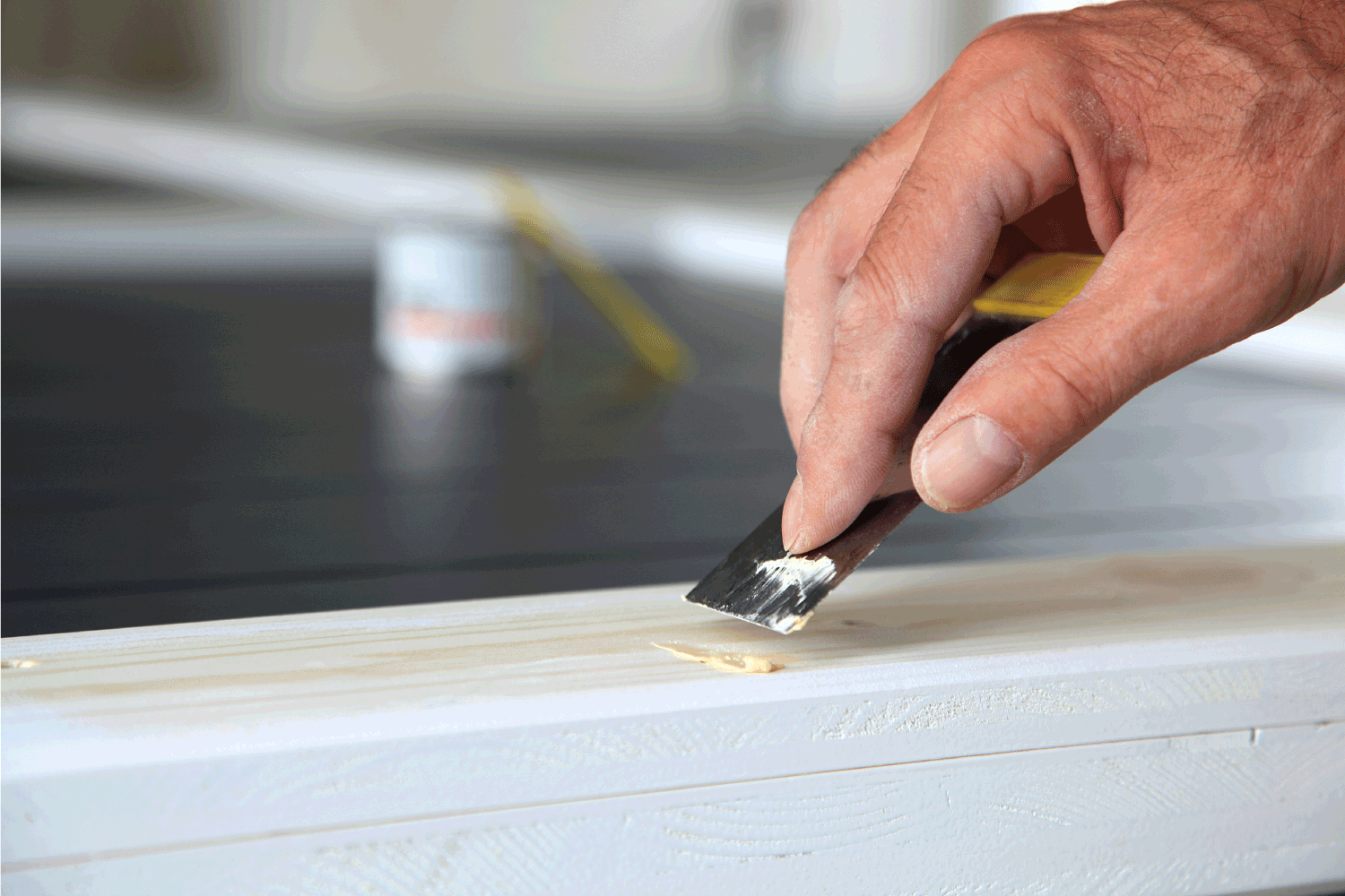 woodwork. Putty knife in man's hand. DIY worker applying filler to the wood. Removing holes from a wood surface