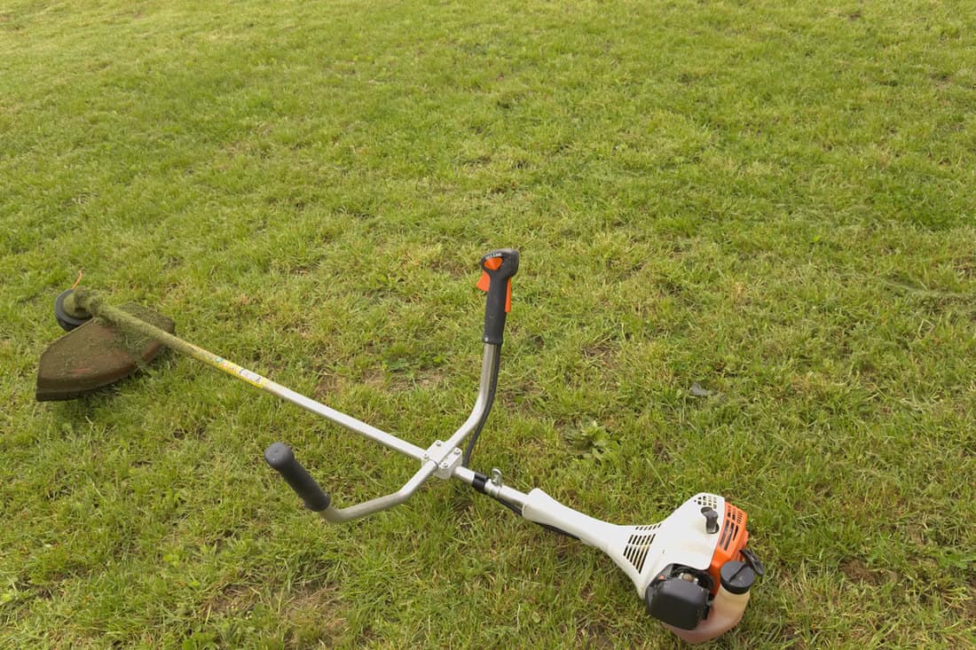 A Stihl weed eater left in a grass field