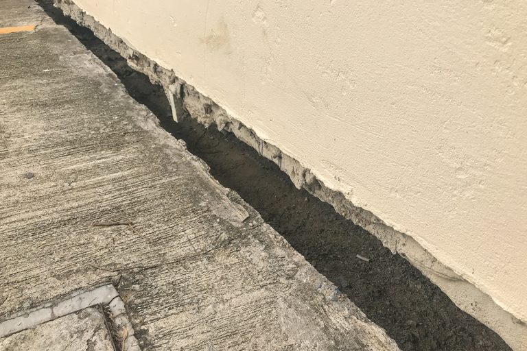 A close up of land subsidence gap between hole and building, Gap Between Foundation And House - What To Do?
