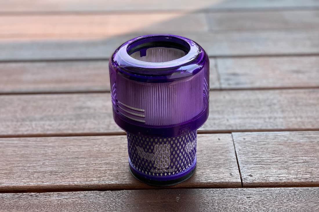 A close up view of Dyson cordless vacuum HEPA filter head on a wooden floor