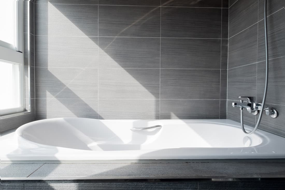 A fitted bathtub inside a gray designed bathroom