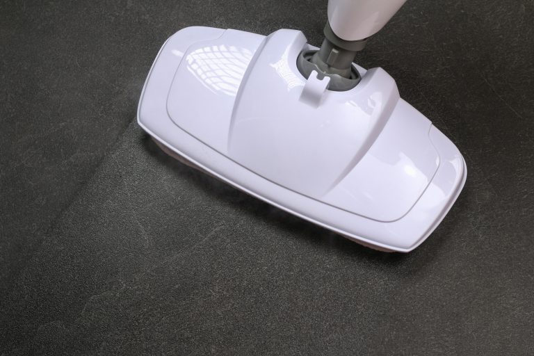 A man washes black porcelain stoneware with a steam mop. Killing germs, clean floor, decontamination - What's The Best Machine To Clean Tile Floors And Grout