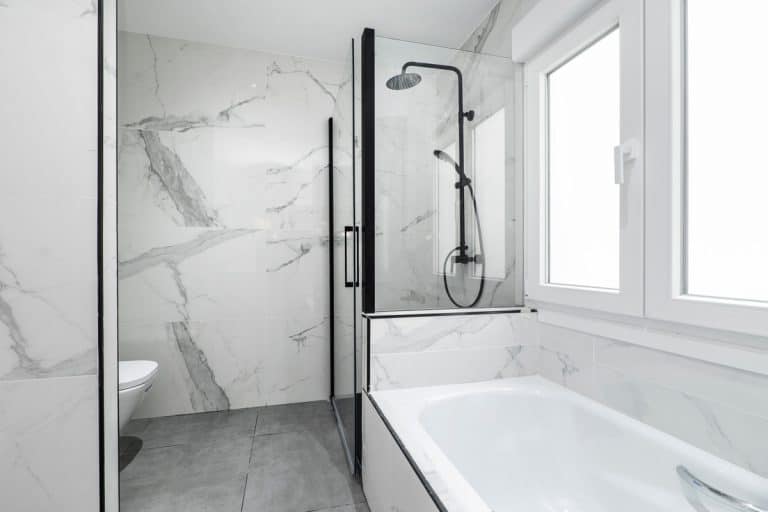 A marble themed bathroom with white painted walls and white metal framed window, How To Fill Large Gap Between Bath And Wall