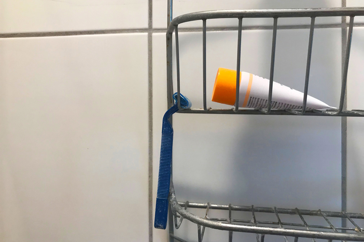 A shaving razor hanging in the shower.