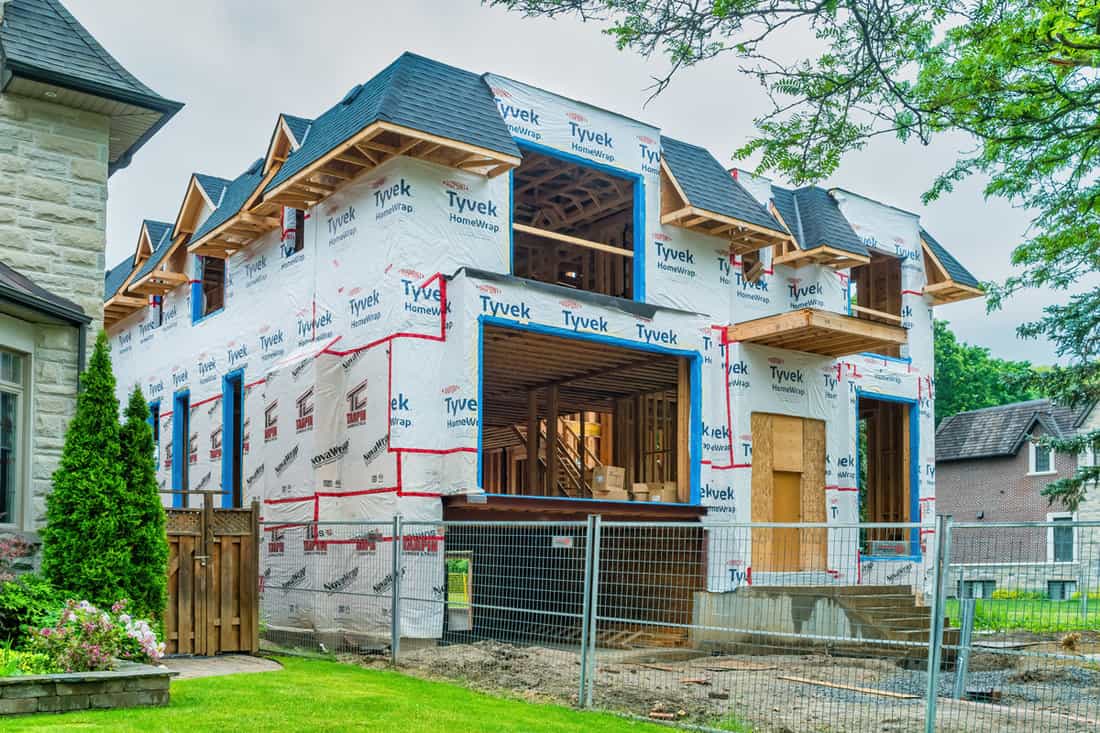 A two story mansion covered in tyvek house wrap