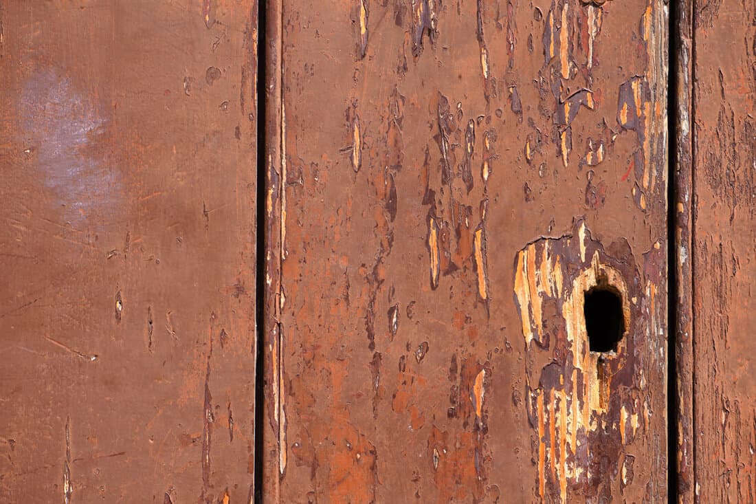 Aged wood background, peeling red paint, hole, old wooden rotten timber