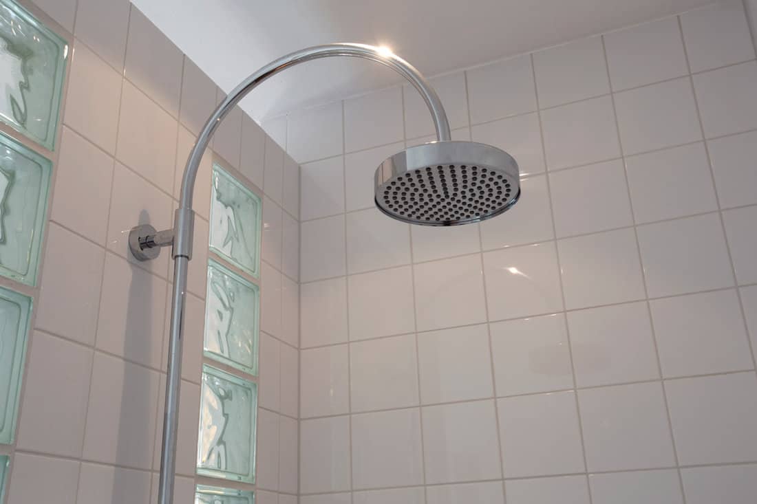 An arched rain shower head inside a modern bathroom