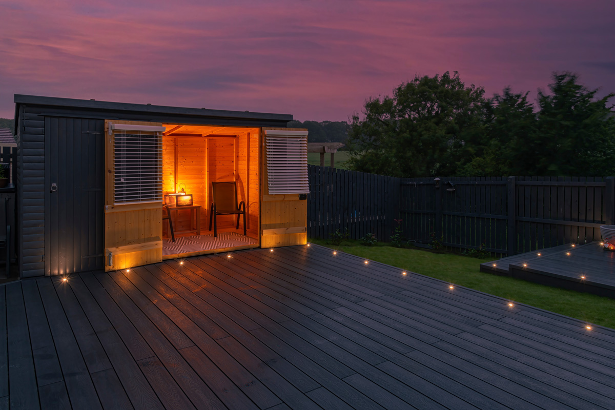 Ash grey composite decking built on two levels on a residential back garden with low voltage deck lights installed as well. 