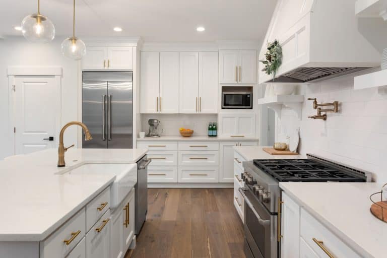 Beautiful kitchen in new luxury home with island, pendant lights, and hardwood floors, How Much Space Between Oven And Kitchen Island?