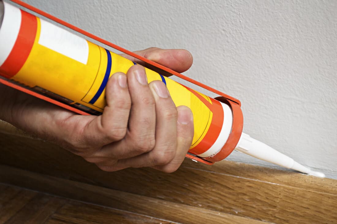 Caulking silicone from cartridge on wooden batten.