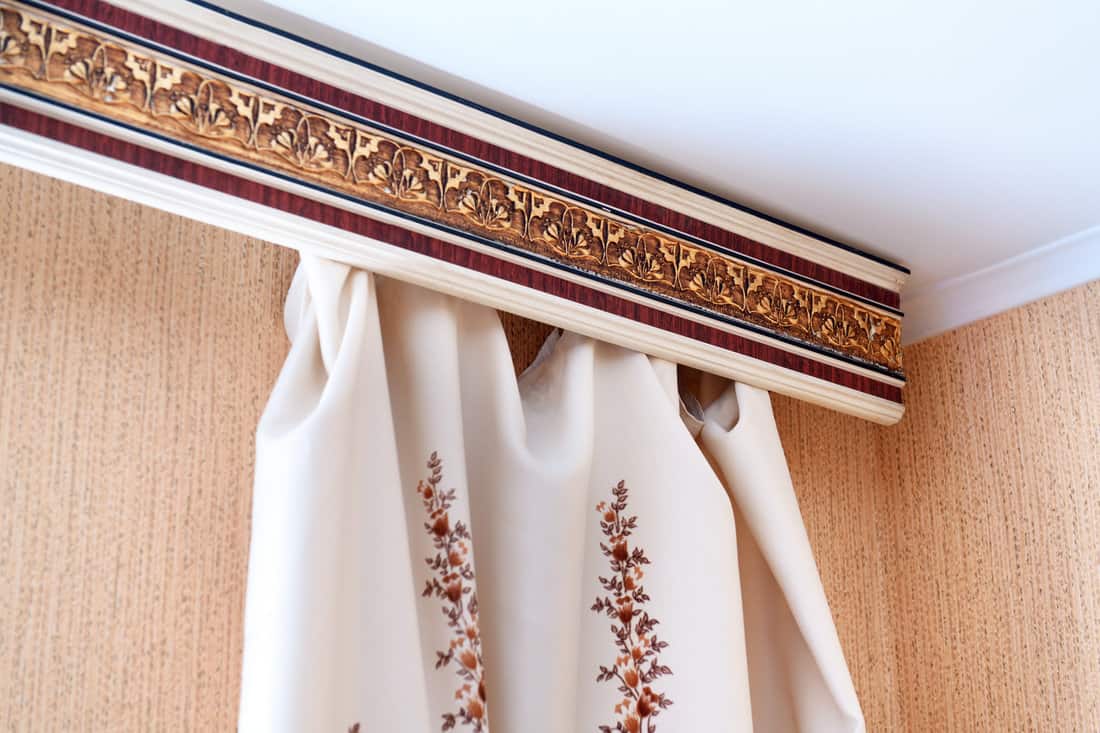 Curtains made of natural fabric and cornice close-up