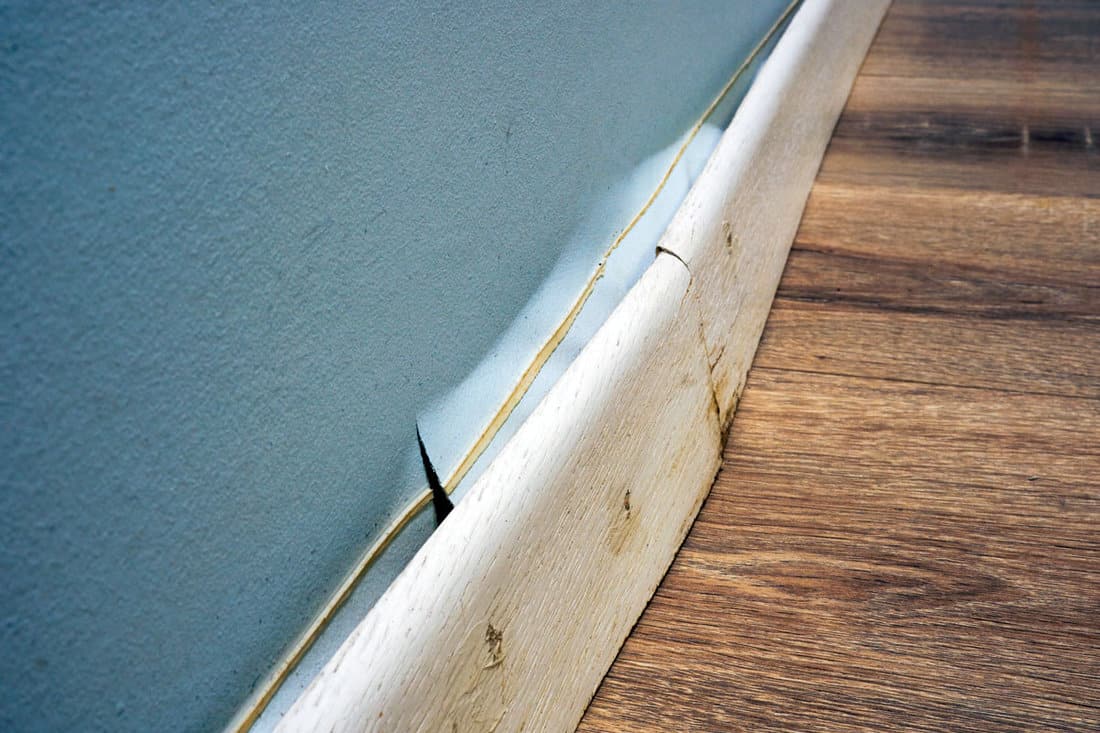 Damaged skirting board detached from the wall after the apartment was flooded