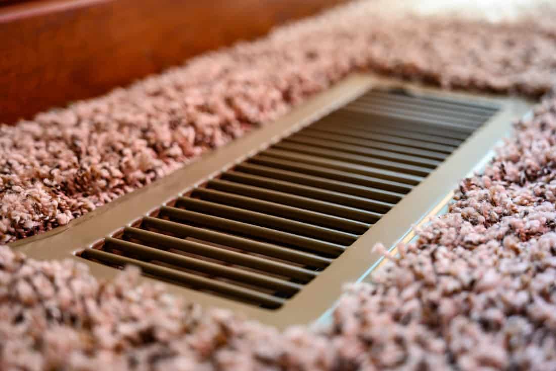 Focus on floor vent in room with carpet