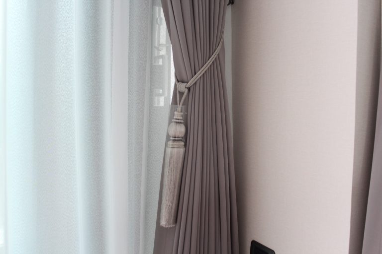 Grey curtains with white sheer curtains with luxury tie back in living room. Mood and tone are in grey and brown colour. - How High Should Curtain Tie Backs Be