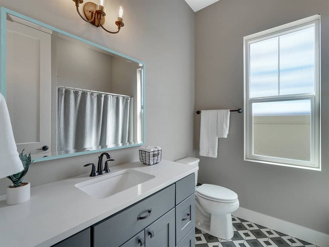 Guest bathroom with gray cabinets and white countertops