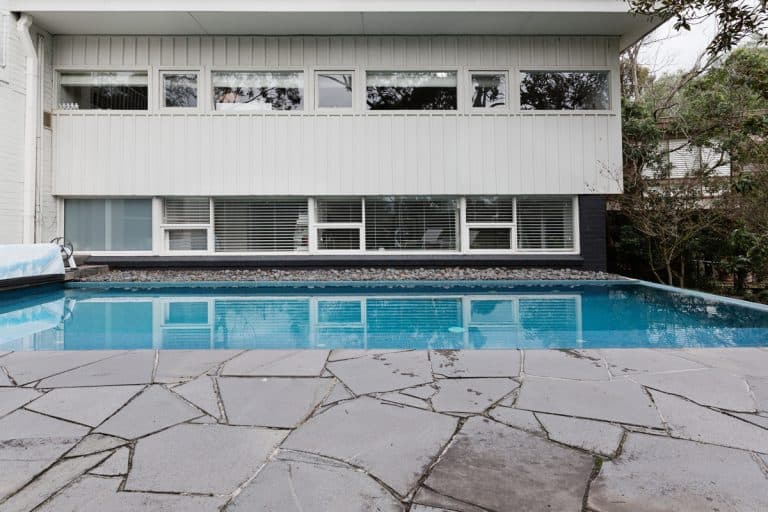 Home with in ground swimming pool and stone paving, 7 Best Decking Materials For Pools