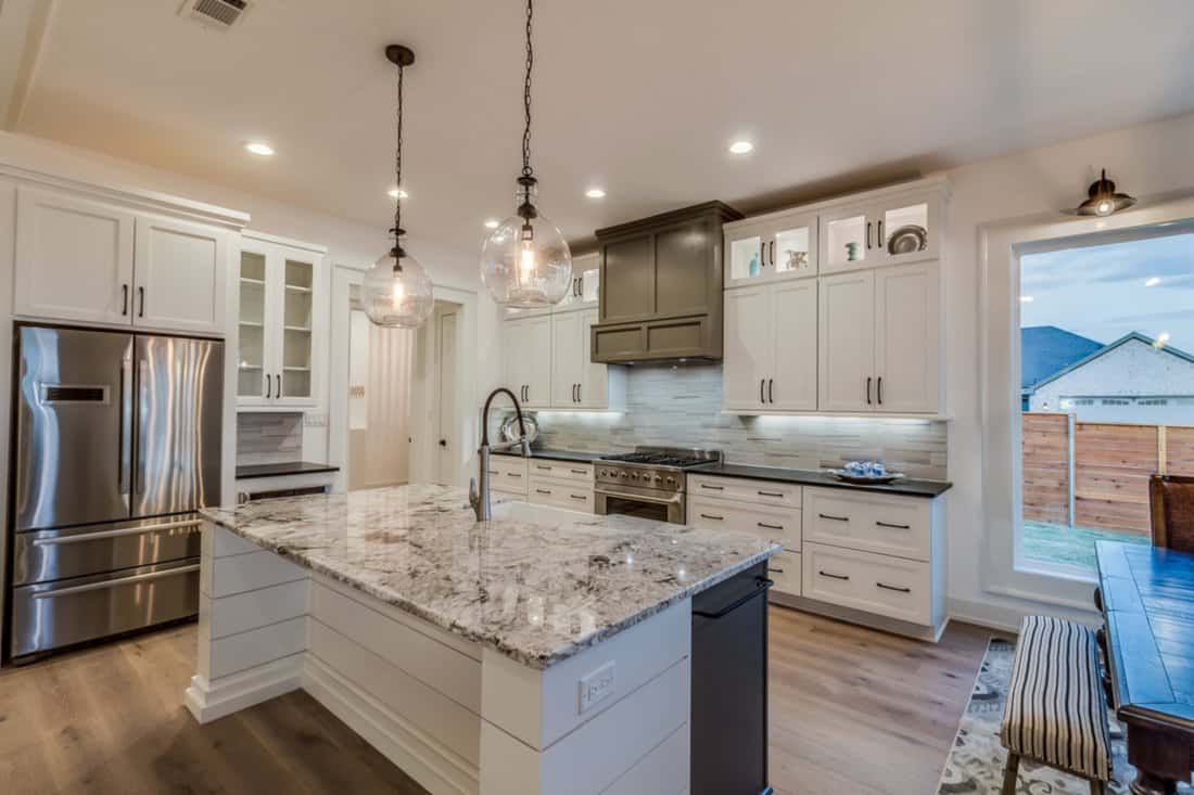 How Far Should Pendant Lights Hang Over An Island - Large appliances and white cabinets in new kitchen
