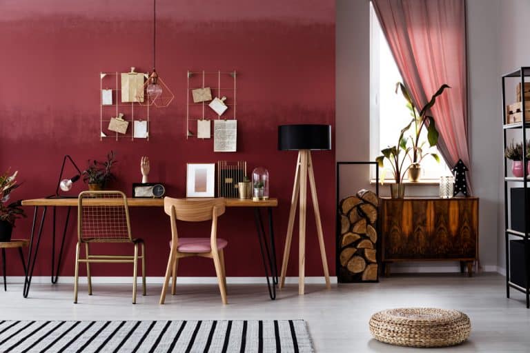 Interior of a modern living room with burgundy painted walls, wooden chairs and white granite flooring, What Color Curtains Go With Burgundy Walls?