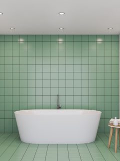 Interior of comfortable bathroom with green tile and white walls, big white bathtub and white toilet - What Color Goes With Green Bathroom Tile