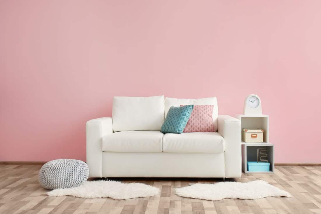 Livingroom interior with grey velvet sofa on pink wall background