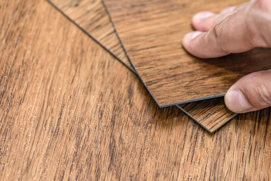 Male hand holding a textured vinyl floor tile