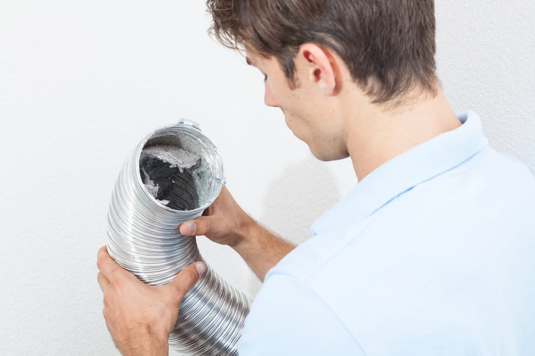 Man cleaning dryer vent in home.