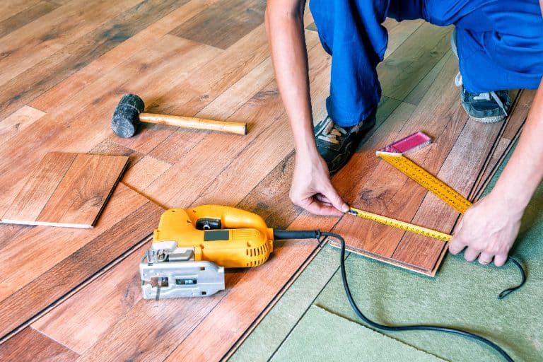 A master carpenter measures the laminate plank, How To Replace Laminate Plank In The Middle Of The Floor