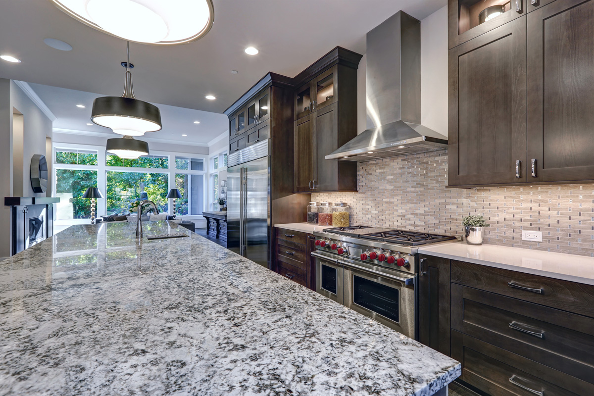Modern kitchen with brown kitchen cabinets, oversized kitchen island, granite countertops