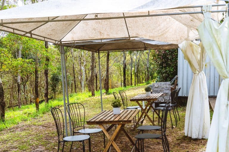 An outdoor cafe dining with a hillside lean, rustic table and chairs under a mildewed tent, How To Keep Outdoor Curtains From Mildewing