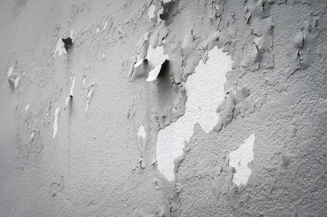 Peeling paint on gray concrete wall.